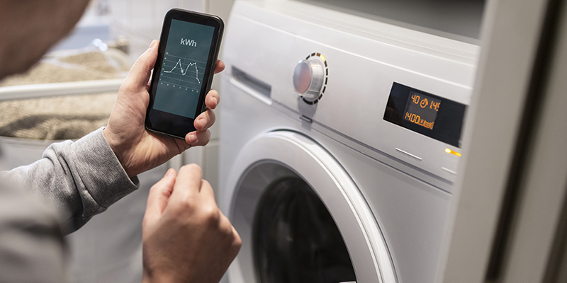 En person styr sin tvättmaskin med sin mobiltelefon.
