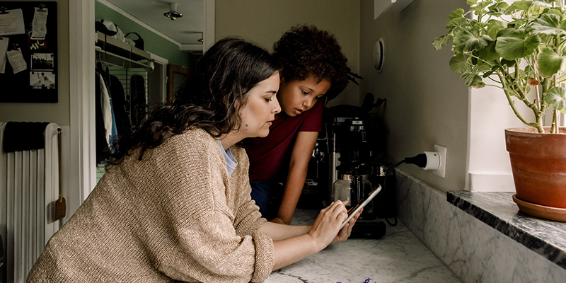 En förälder och ett barn tittar på en mobiltelefon.
