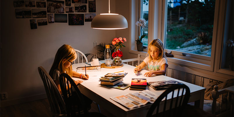 Två flickor sitter vid ett bord och ritar.