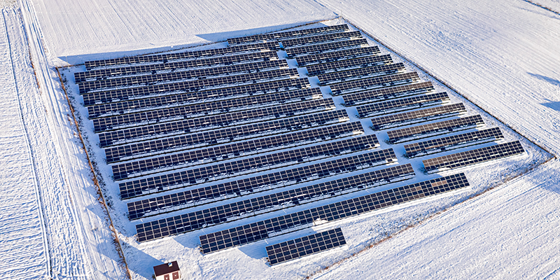 Solceller med snö på den omkringliggande marken.